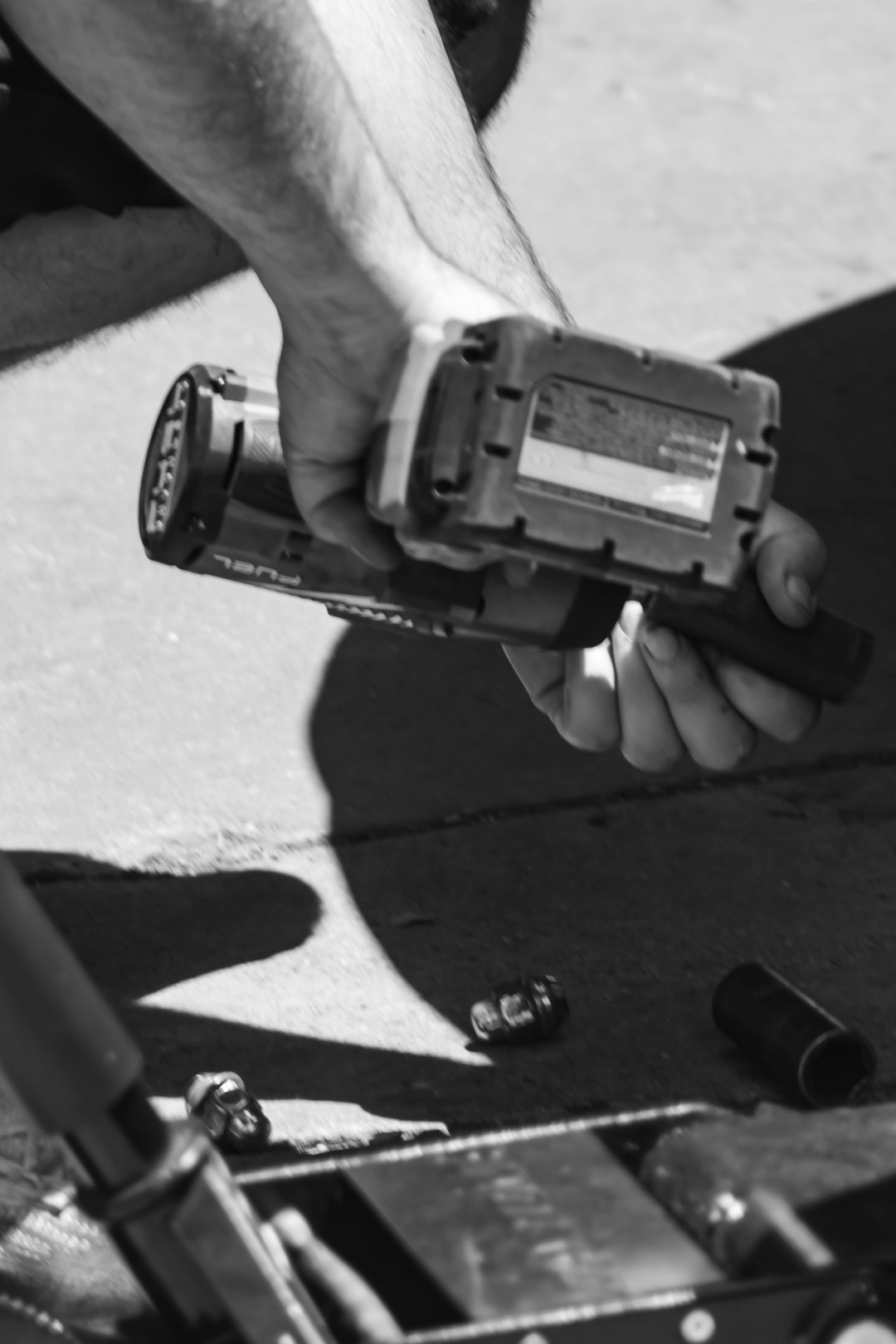 Monochromatic photograph of hands changing lug nuts with a commercial power drill.
