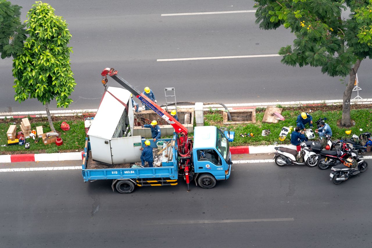 Overhead shot of workers with a truck and motorcycles on a city street.